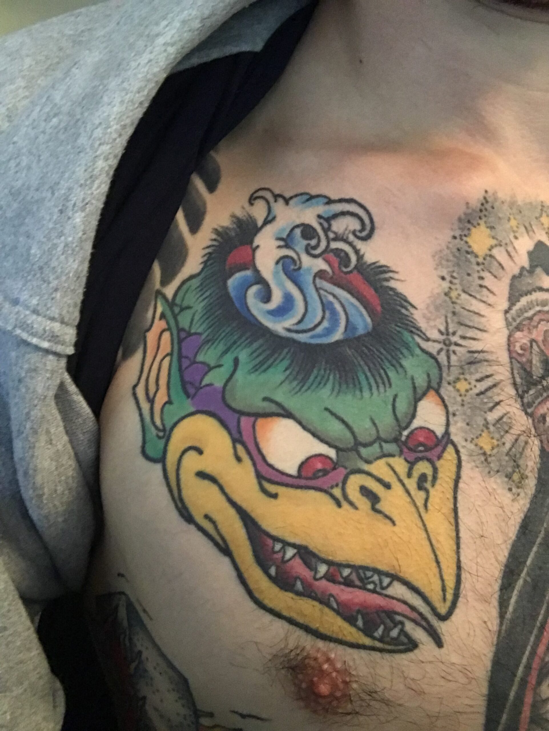 Close view of the green and yellow Kappa chest tattoo by Igor Mortis.