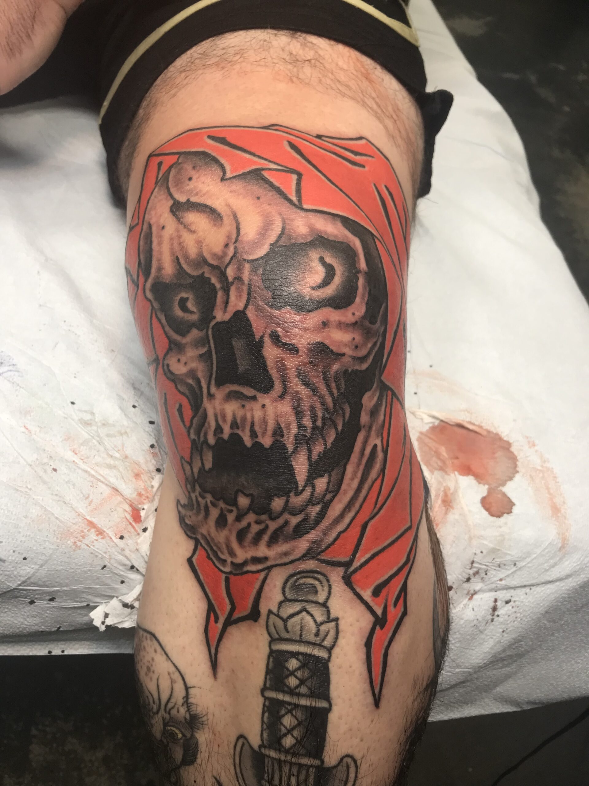 Front view of the fresh skull reaper knee tattoo by Tony Hundahl.